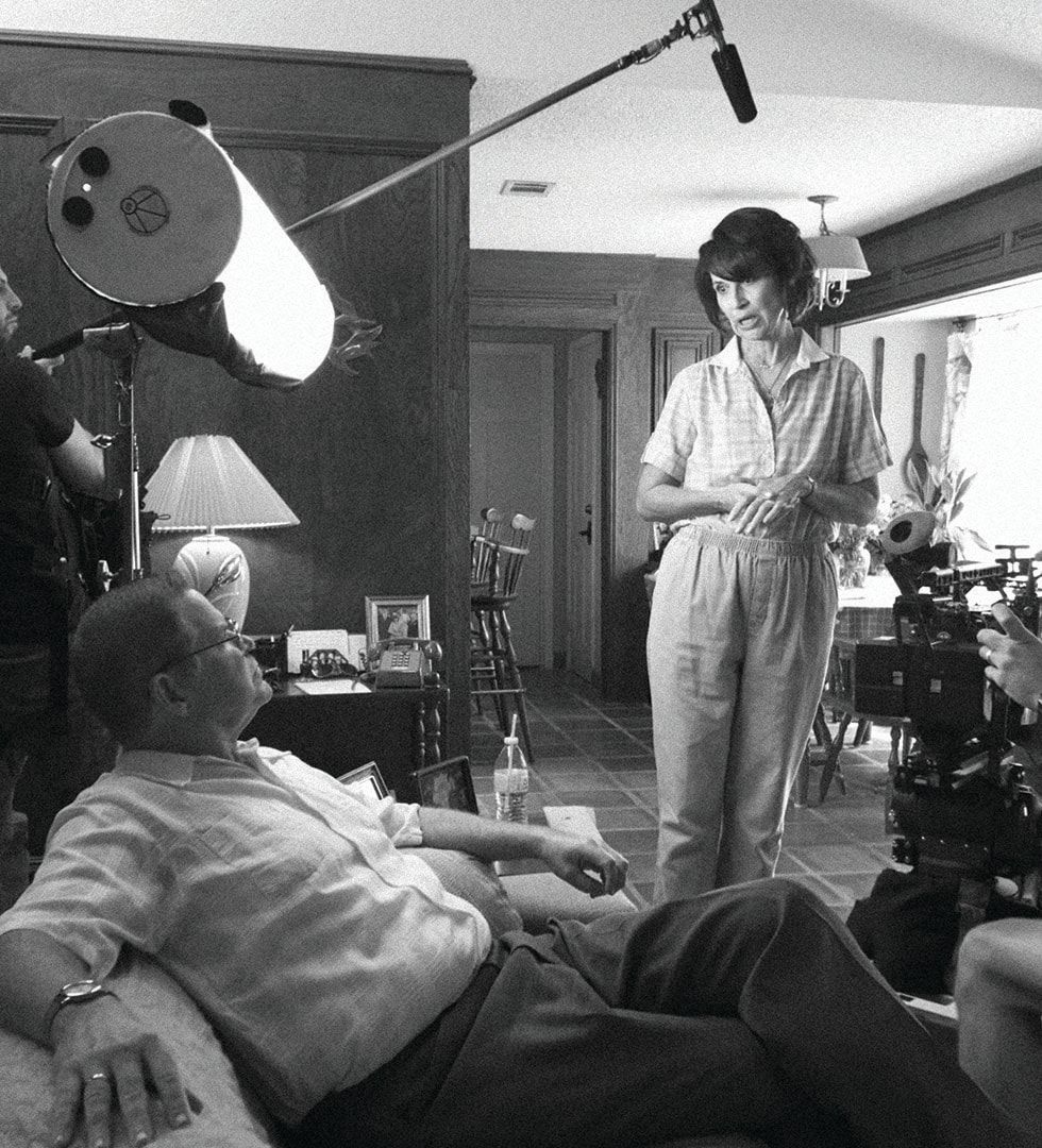 A scene on the couch in black and white, with a boom and a light hanging over the actors